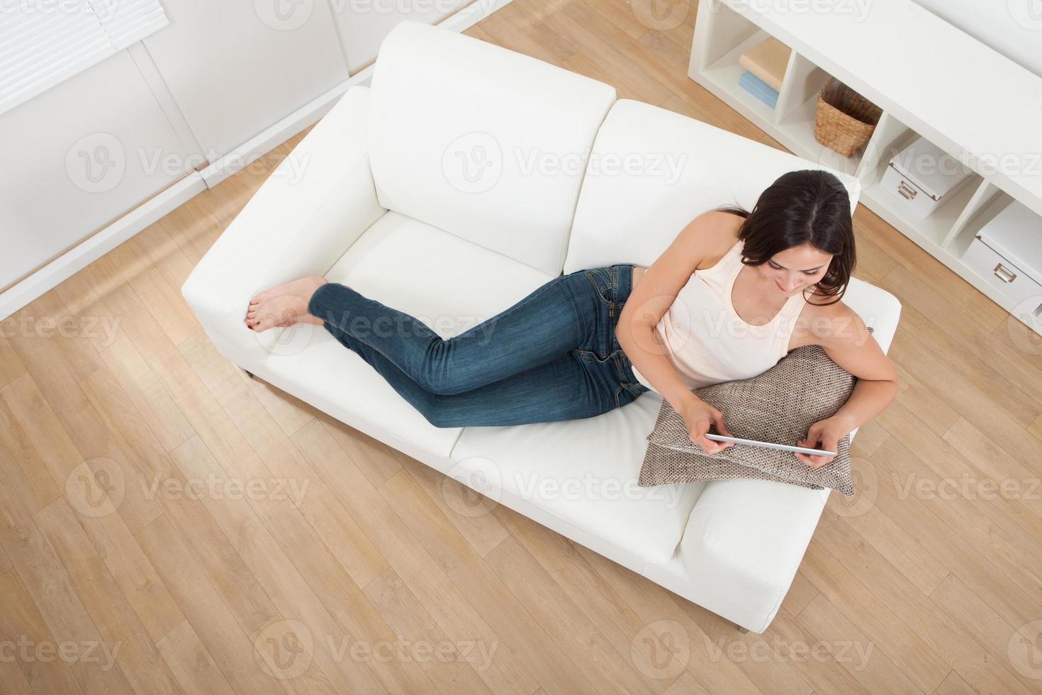 ung kvinna med digital tablet på soffan foto