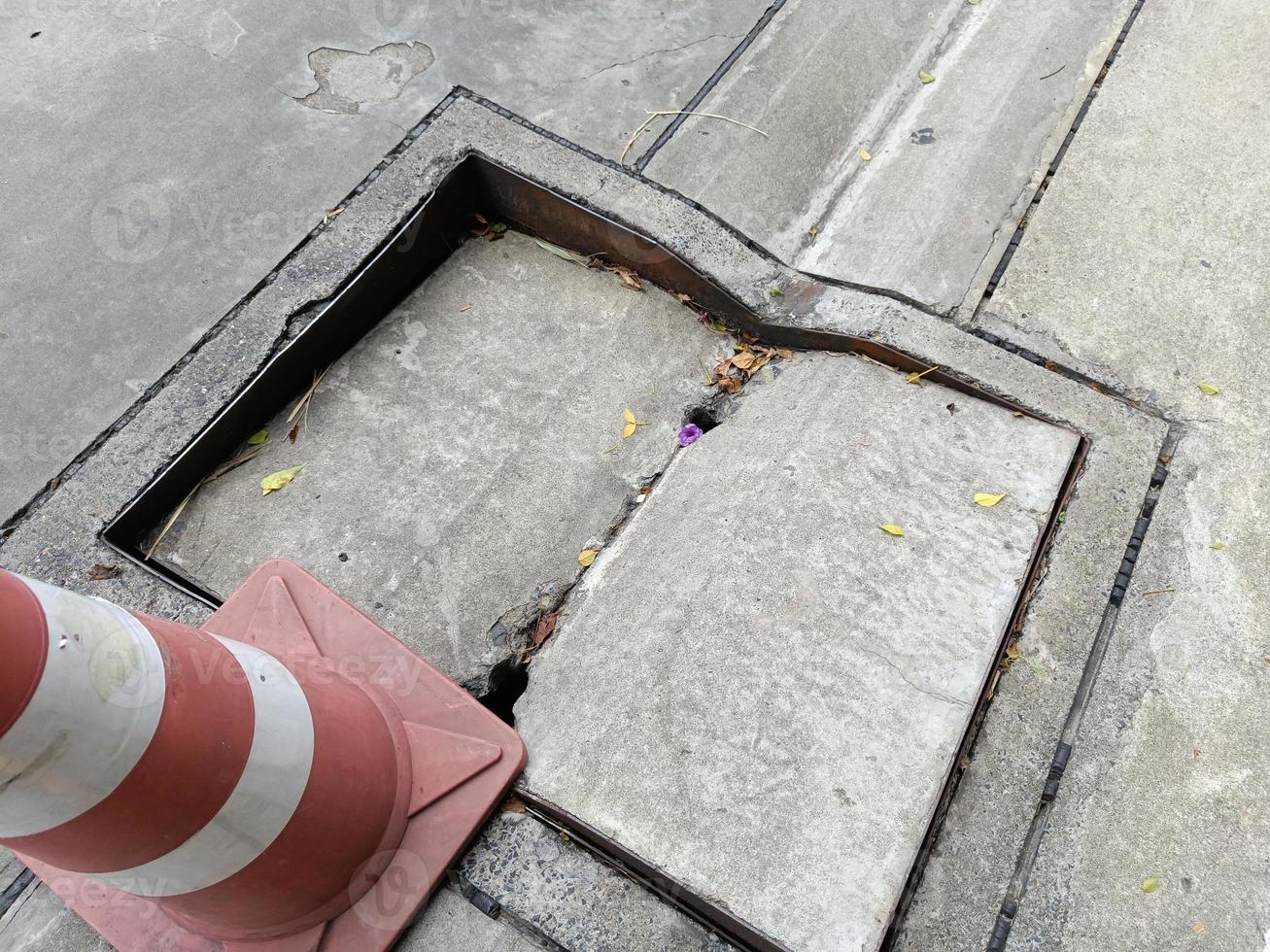 skadat gammalt brunnslock på gångväg. trasig cementrörslock är inte säkert att gå. foto