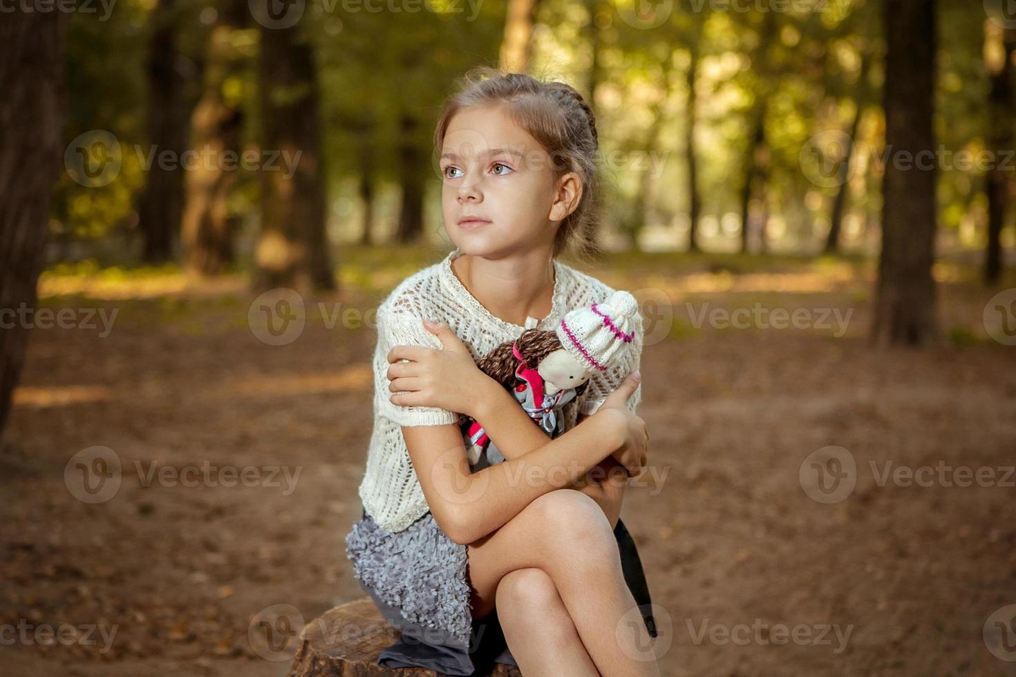 charmig liten flicka i skogen med dockan foto
