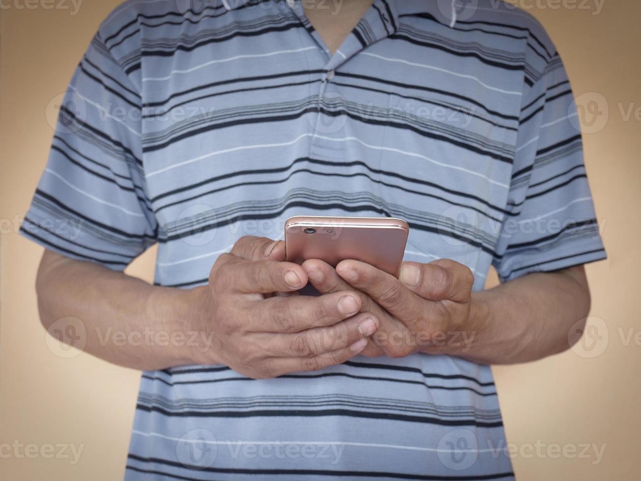 en asiatisk man som bär en blårandig skjorta som står och håller i en telefon foto