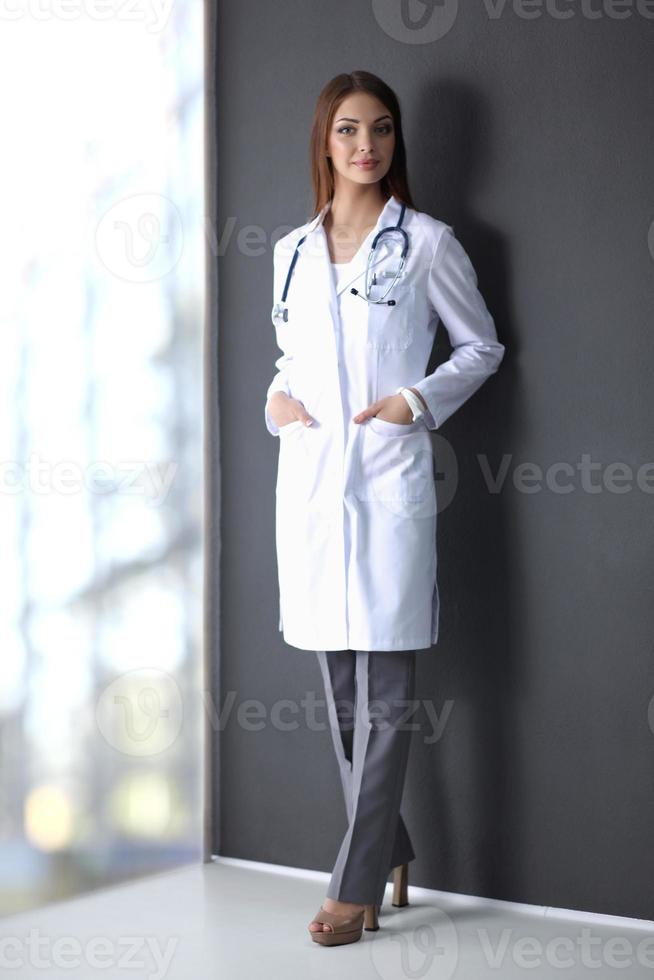 läkarkvinna med stetoskop isolerad på grå bakgrund foto