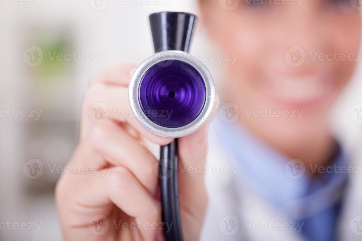 närbild av kvinnlig läkare med stetoskop, fokus på stetosco foto