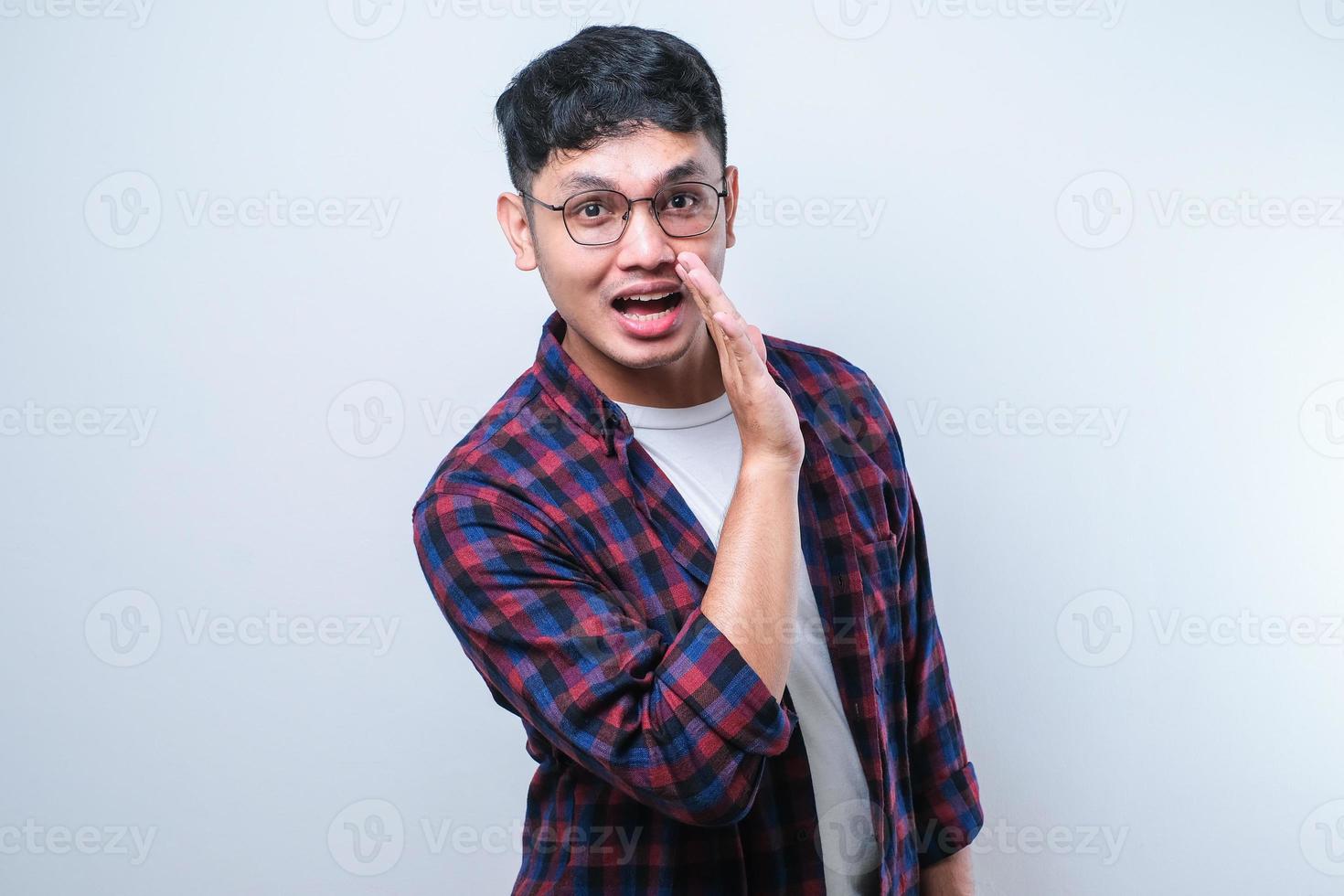 ung asiatisk man handen på munnen berättar hemliga rykten, viskar skadlig pratkonversation foto