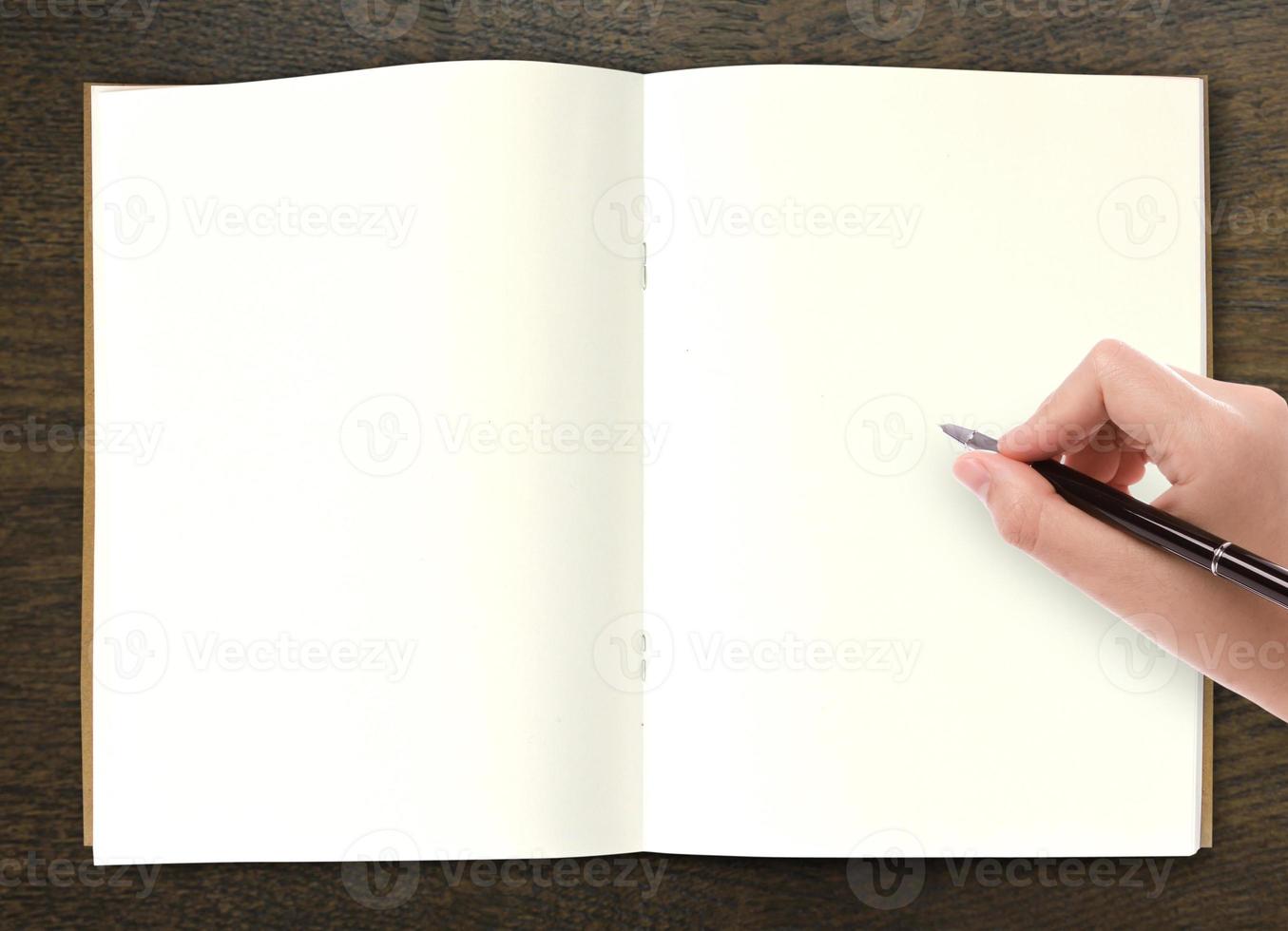 hand skriva i öppen bok på bordet foto