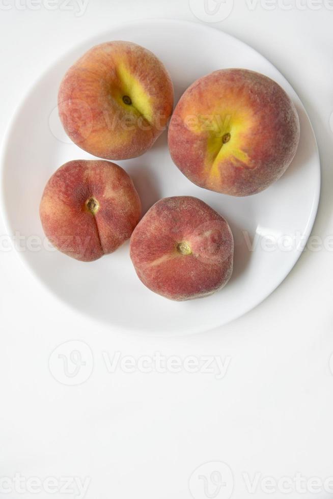 saftiga röda och gula persikor på en vit platta. läckra persikor till lunch. foto