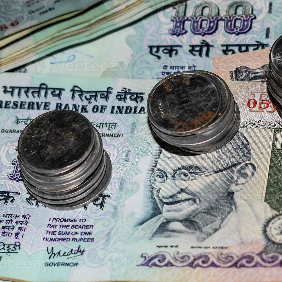 sällsynta gamla indiska bankrupiemynt som faller på valutasedlar, faller ner indiska rupiermynt på hundrarupiesedlar, indiska valutamynt faller foto