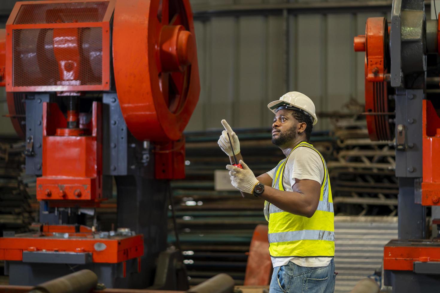 afrikansk amerikansk industriarbetare använder walkie talkie medan han arbetar inne i metallplåtsförzinkade takfabriken för säkerhetsindustrikoncept foto