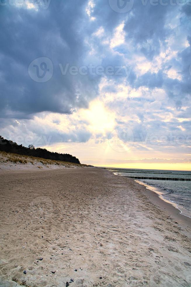 på Östersjöns strand. solnedgång, groynes, strand och sand. landskapsbild foto