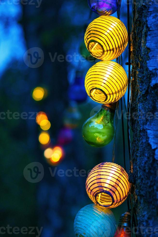 sträng av ljus hängande på trädet. trädgårdsfest. romantisk plats. färgstarkt ljus foto