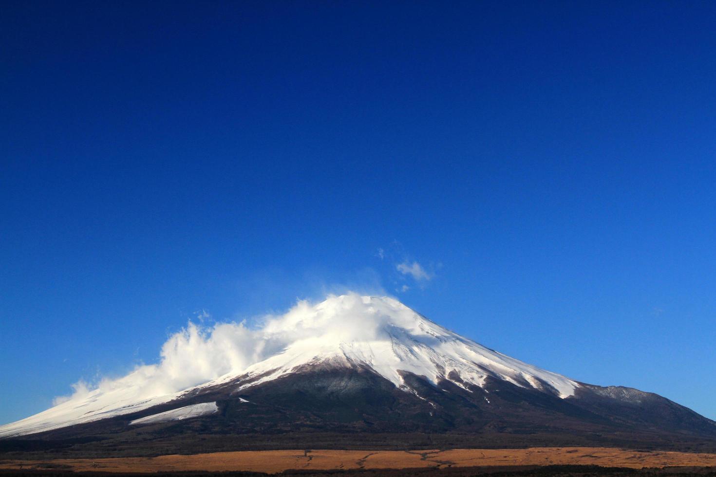 Fuji berg med snö och dimma täckt topp, sjö eller hav och klarblå himmel bakgrund med kopia utrymme. denna plats känd i Japan och Asien för människor som reser för att besöka och ta bilder. foto