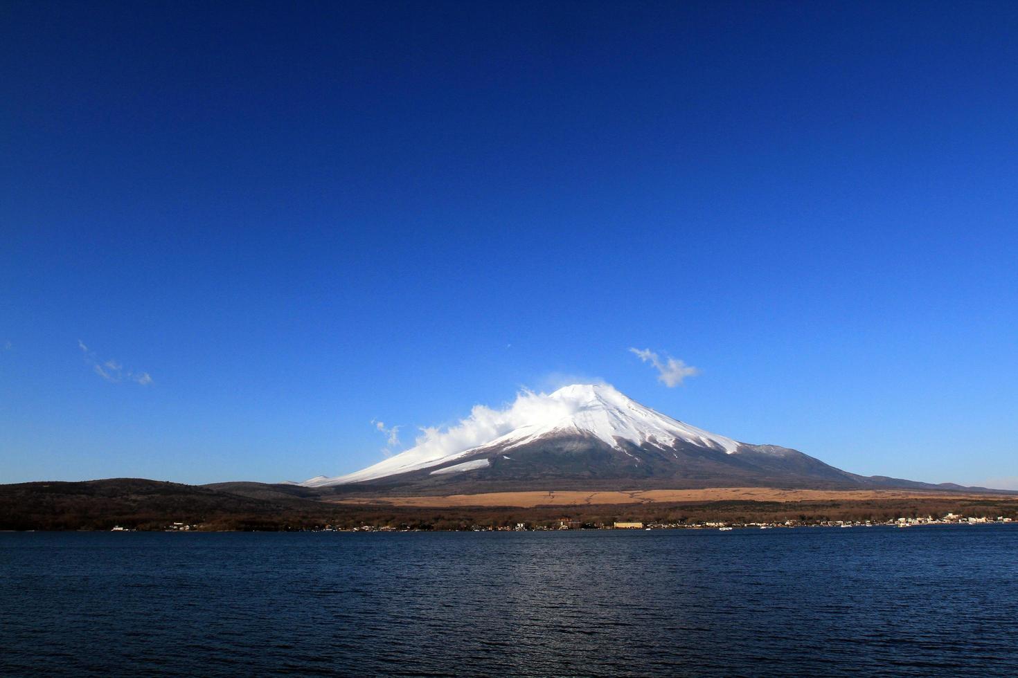 Fuji berg med snö och dimma täckt topp, sjö eller hav och klarblå himmel bakgrund med kopia utrymme. denna plats känd i Japan och Asien för människor som reser för att besöka och ta bilder. foto