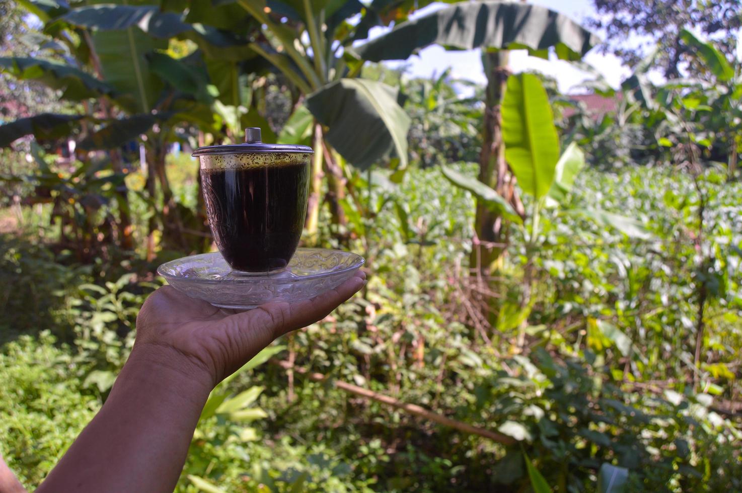 närbild av hand som håller en kopp kaffe utomhus foto