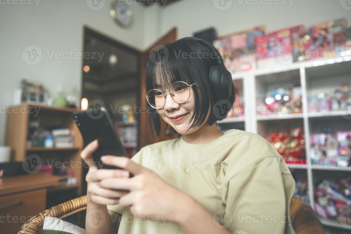 ung vuxen asiatisk kvinna bär hörlurar lyssna på musik och koppla av med smartphone för att koppla av hemma foto