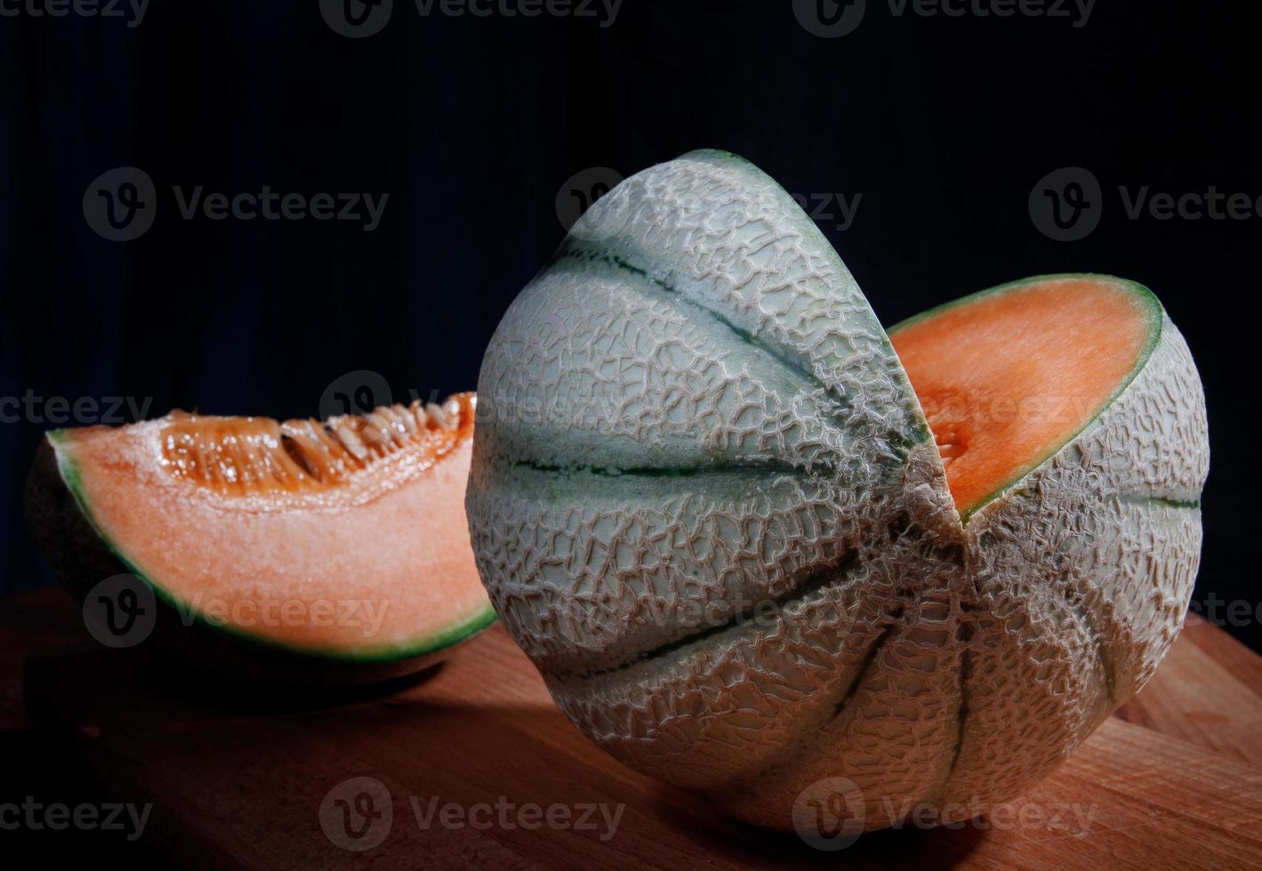 vacker mogen melon och en bit melon på en träskiva. foto