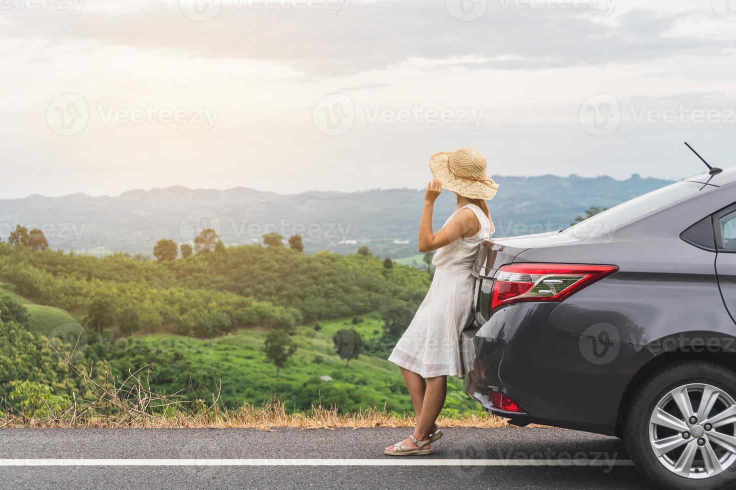 ung kvinna resenär ser vackert landskap med bil på roadtrip, sommarsemester foto