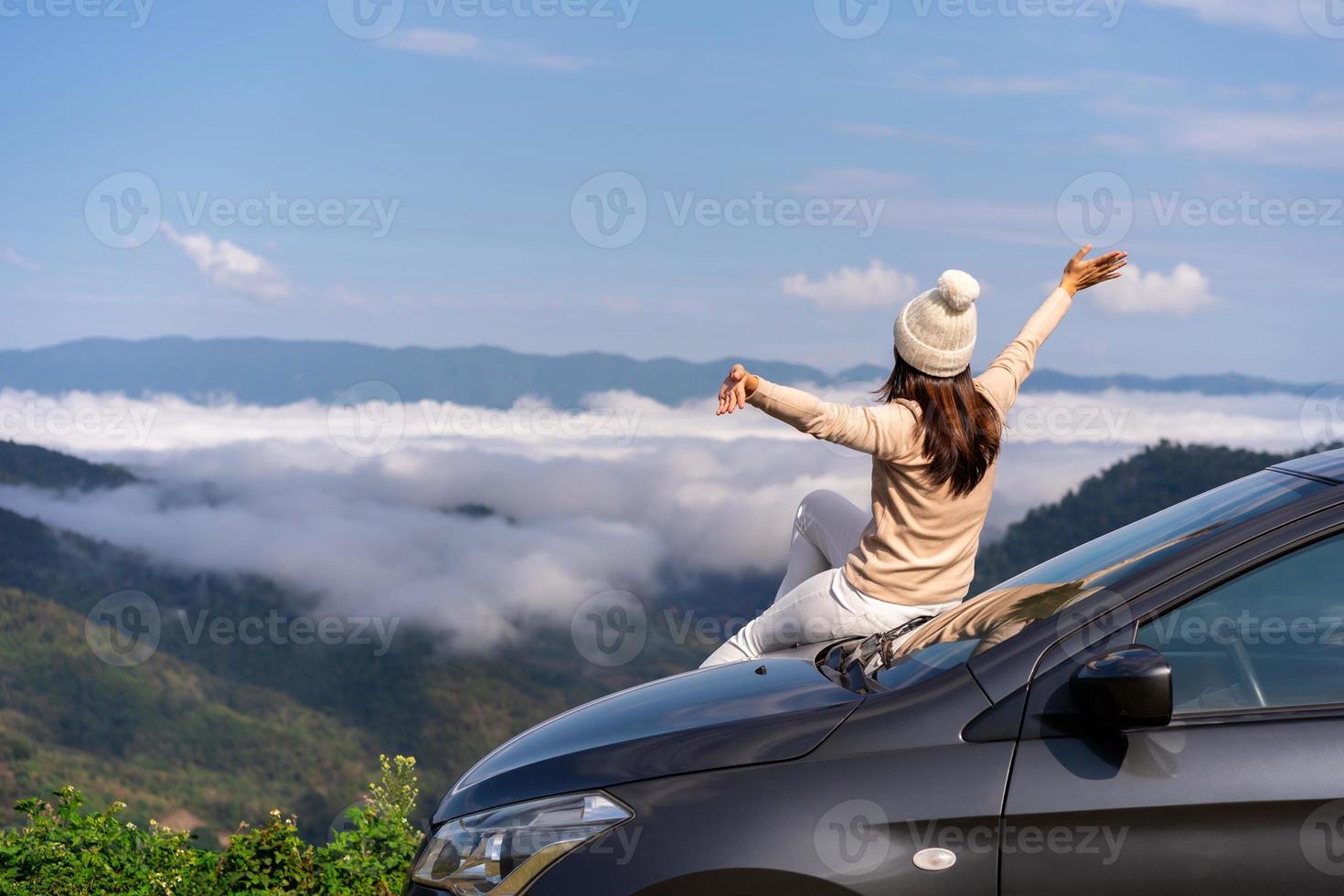 ung kvinna resenärer med bil tittar på ett vackert hav av dimma över berget medan resa kör bilresa på semester foto