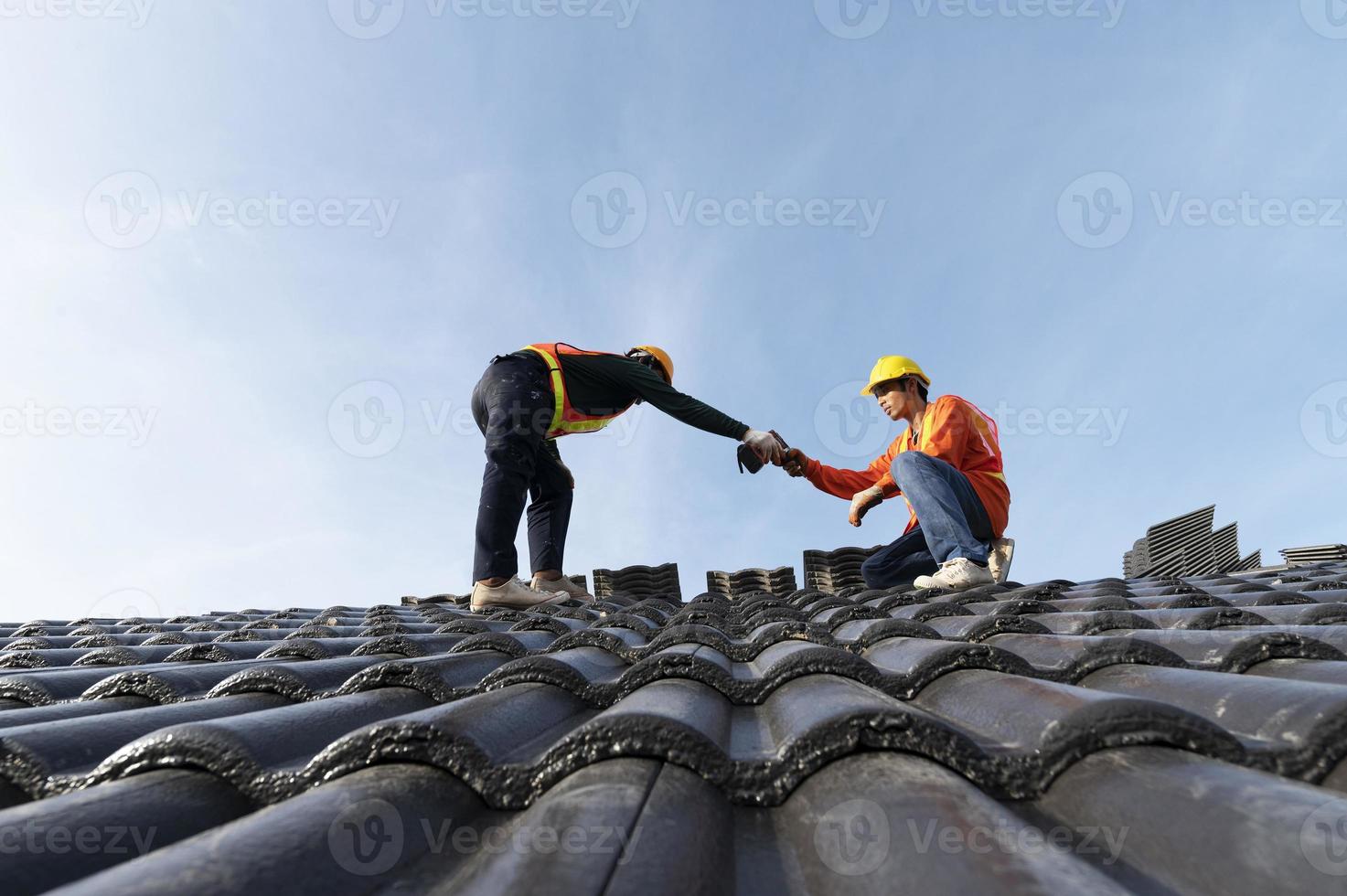 byggare i arbetskläder installerar nya takverktyg, takverktyg, elektrisk borr och använder dem på nya trätak med plåt foto