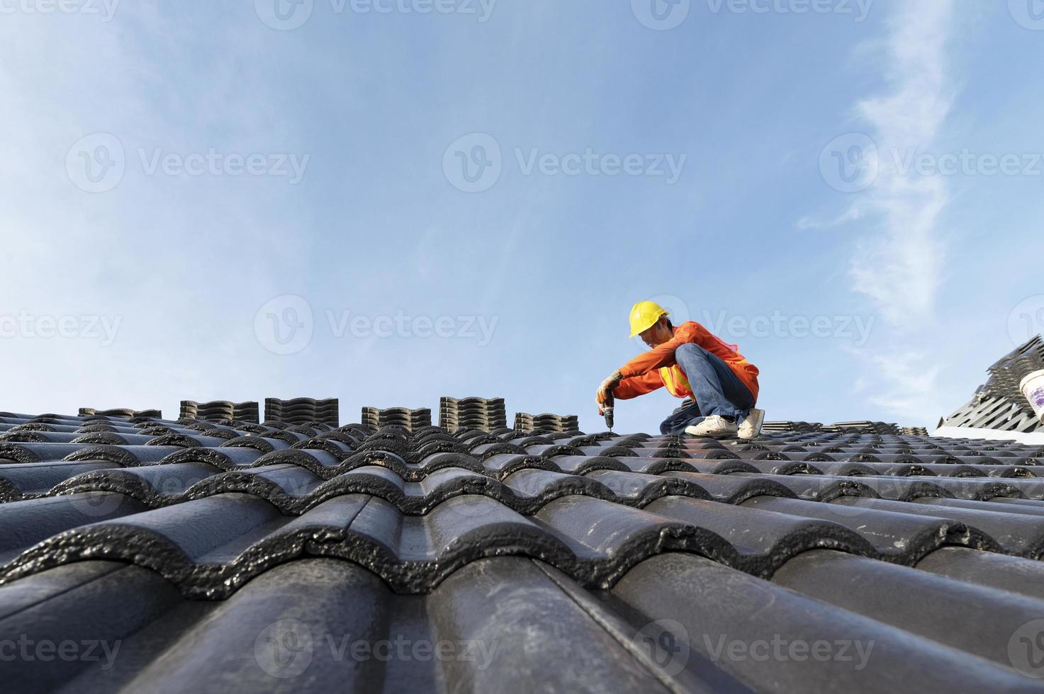 byggare i arbetskläder installerar nya takverktyg, takverktyg, elektrisk borr och använder dem på nya trätak med plåt foto