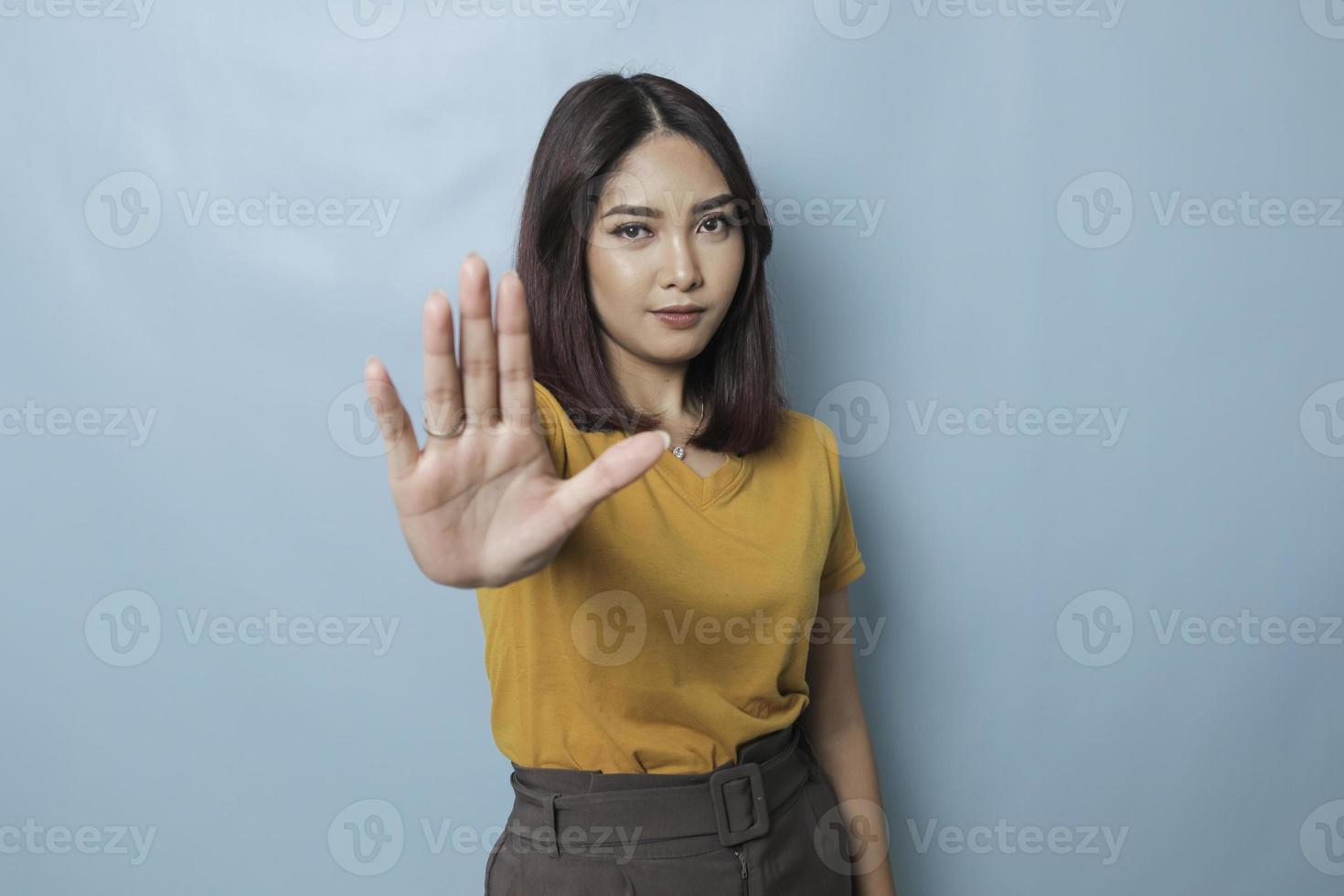 ung asiatisk kvinna som bär casual t-shirt över blå isolerad bakgrund gör stoppskylt med handflatan. foto