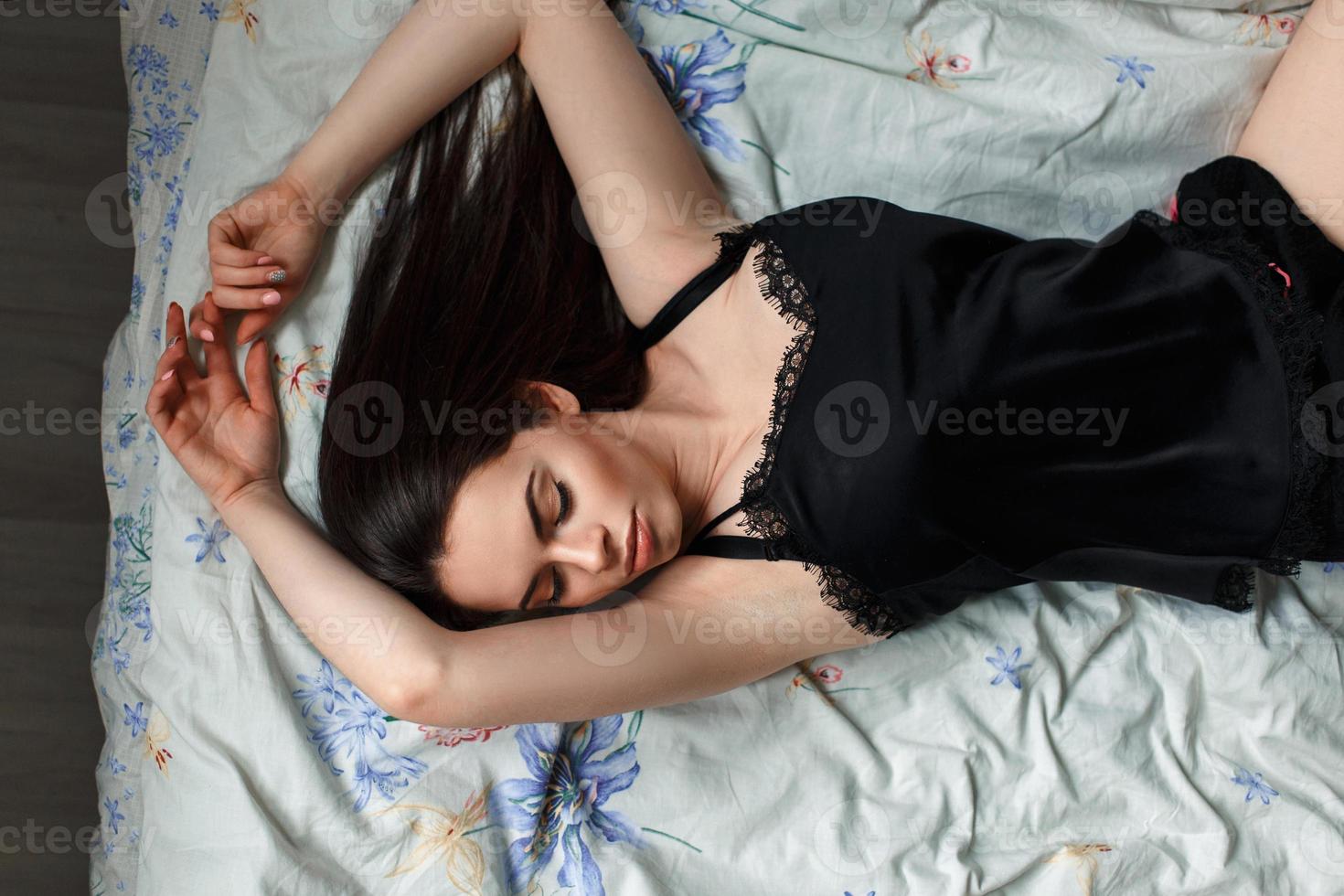 flicka i en svart nattlinne liggande på sängen foto