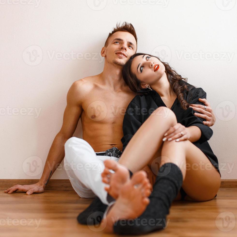 porträtt av ett lyckligt ungt par som sitter på golvet och tittar upp. foto