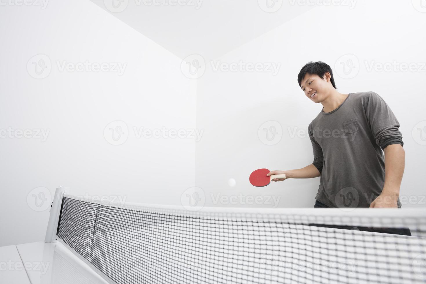 asiatisk mitten av vuxen man som spelar ping-pong foto