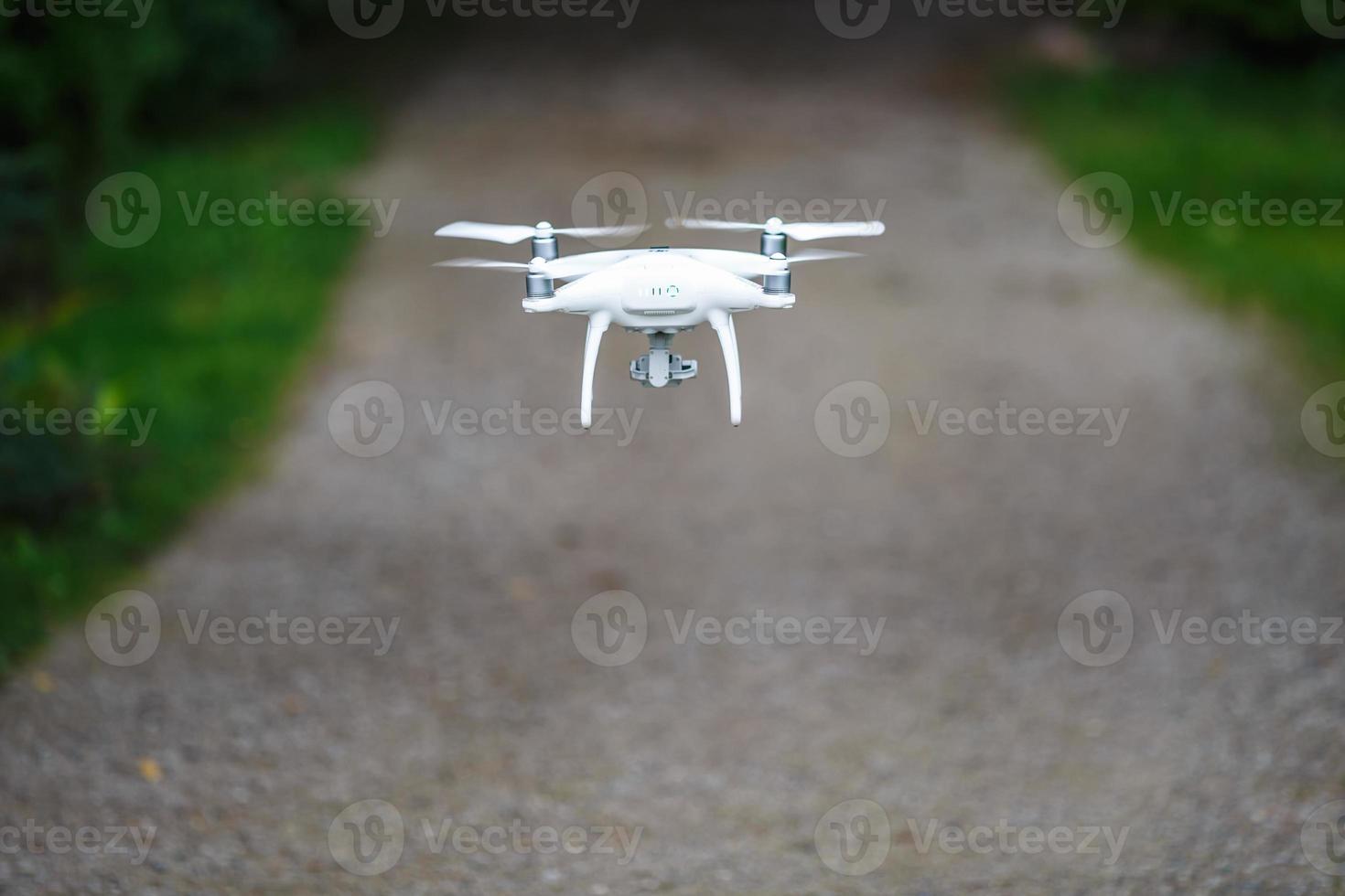 vit flygande quadrocopter med kamera på grön skog bakgrund foto