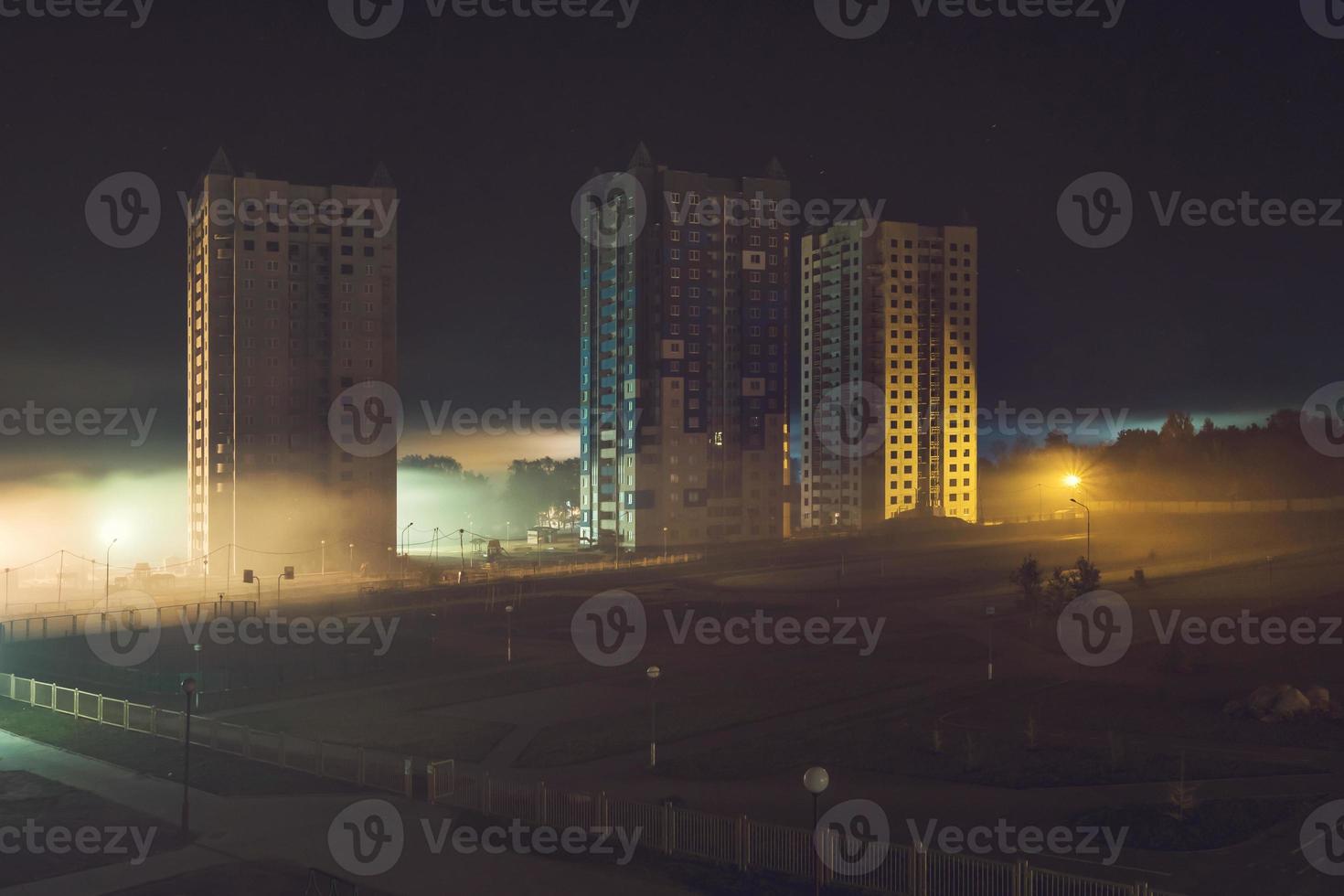 nattpanorama över bostadsområde med höghus i dimman tidigt på morgonen foto