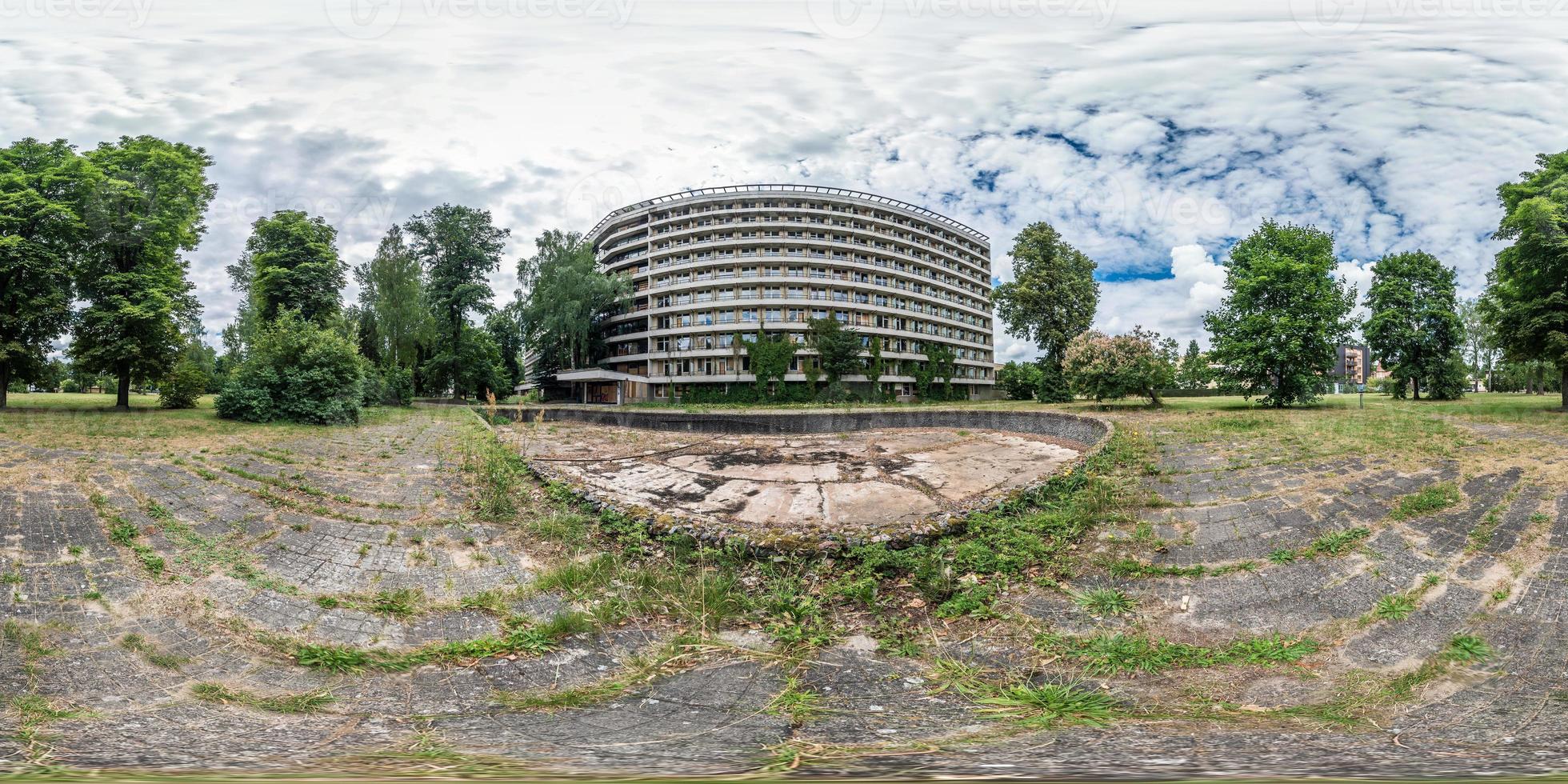 fullständig sömlös panorama 360 gånger 180 graders vinkel vy fasad av övergivna flervånings, kollapsande hotell nära torr tom fontän i ekvirektangulär sfärisk ekvidistant projektion. vr ar innehåll foto