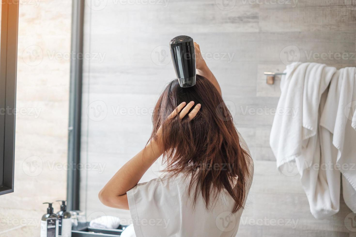 ung kvinna som använder hårtork hemma eller på hotellet. frisyrer och livsstilskoncept foto