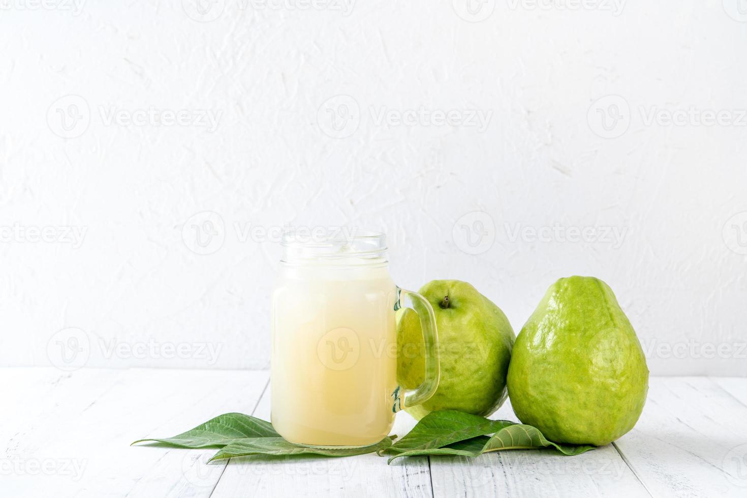 utsökt guava frukt med färsk juice på vit träbord bakgrund. foto