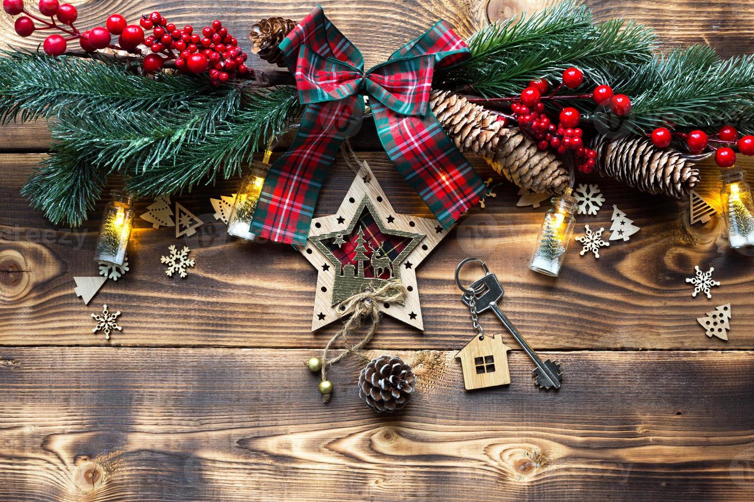 husnyckel med nyckelring stuga på en festlig miljövänlig, naturlig bakgrund med julgran. gott nytt år-röd bakgrund, gåva, gratulationskort. köp, byggnation, flytt, inteckning foto