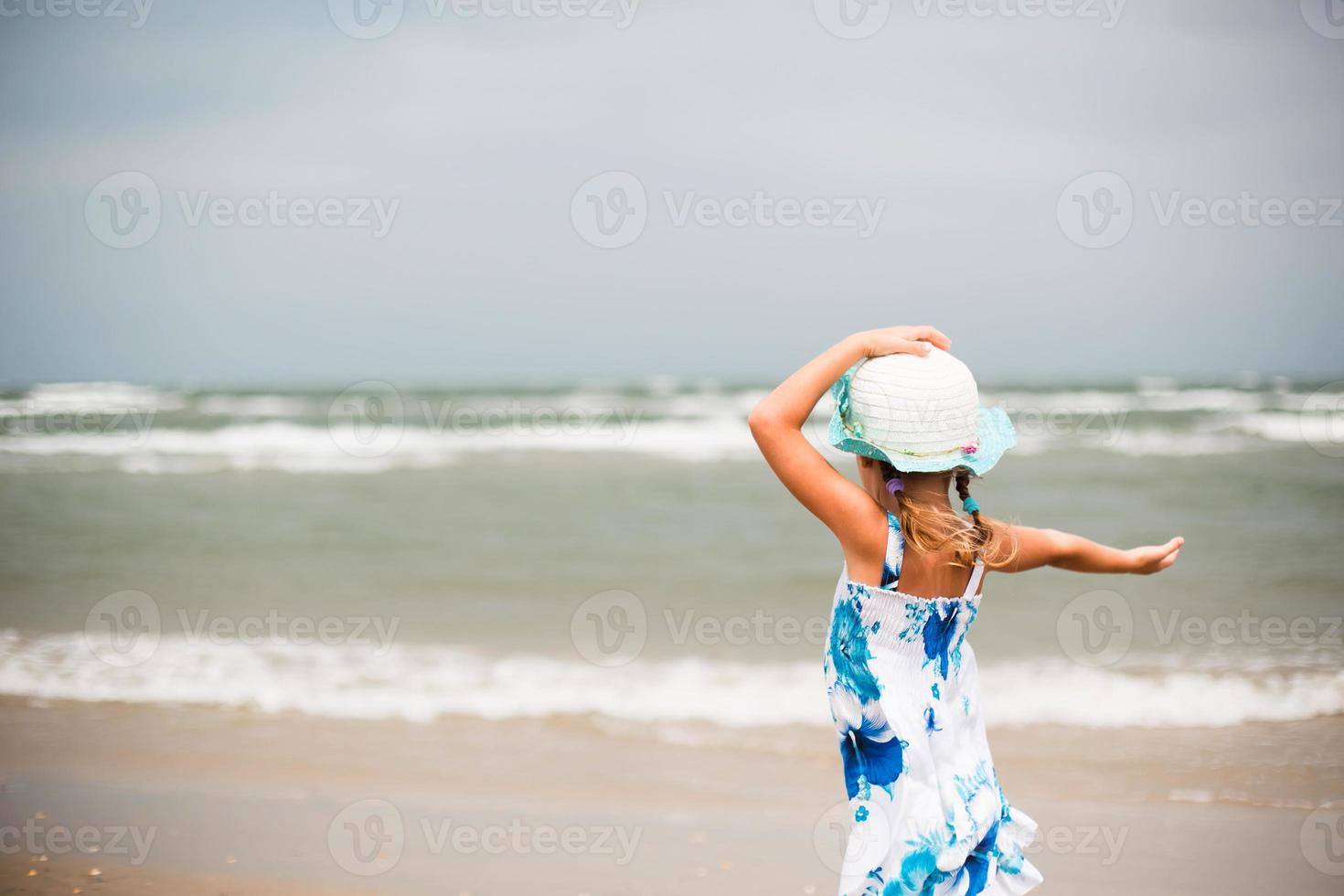 porträtt av en flicka på stranden. barnet njuter av vågorna, kopplar av på stranden, reser. foto