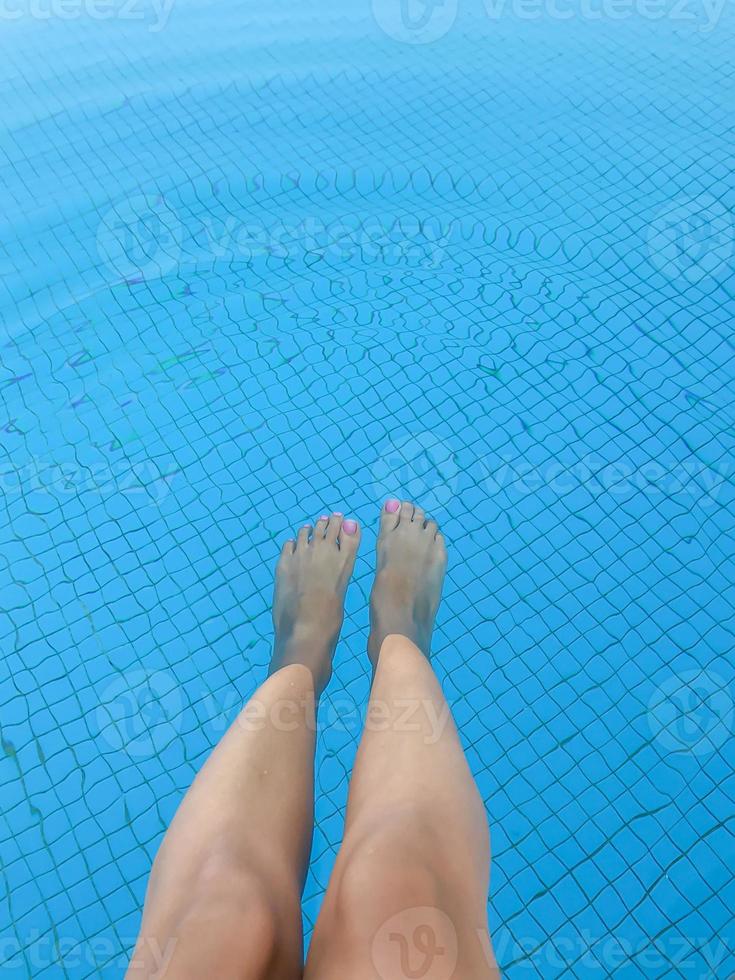 par kvinnas fötter med rosa manikyr på blå poolbakgrund foto