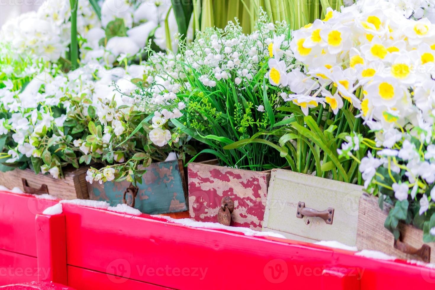 blommande blommor i dekorativa trälådor som står på röd vagn foto