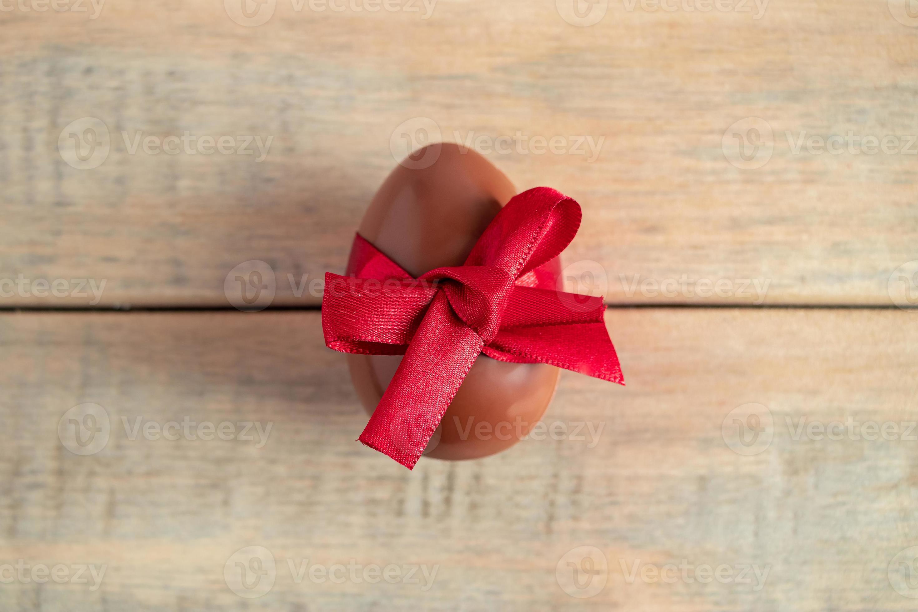 chokladägg med rött band på en träbakgrund. foto