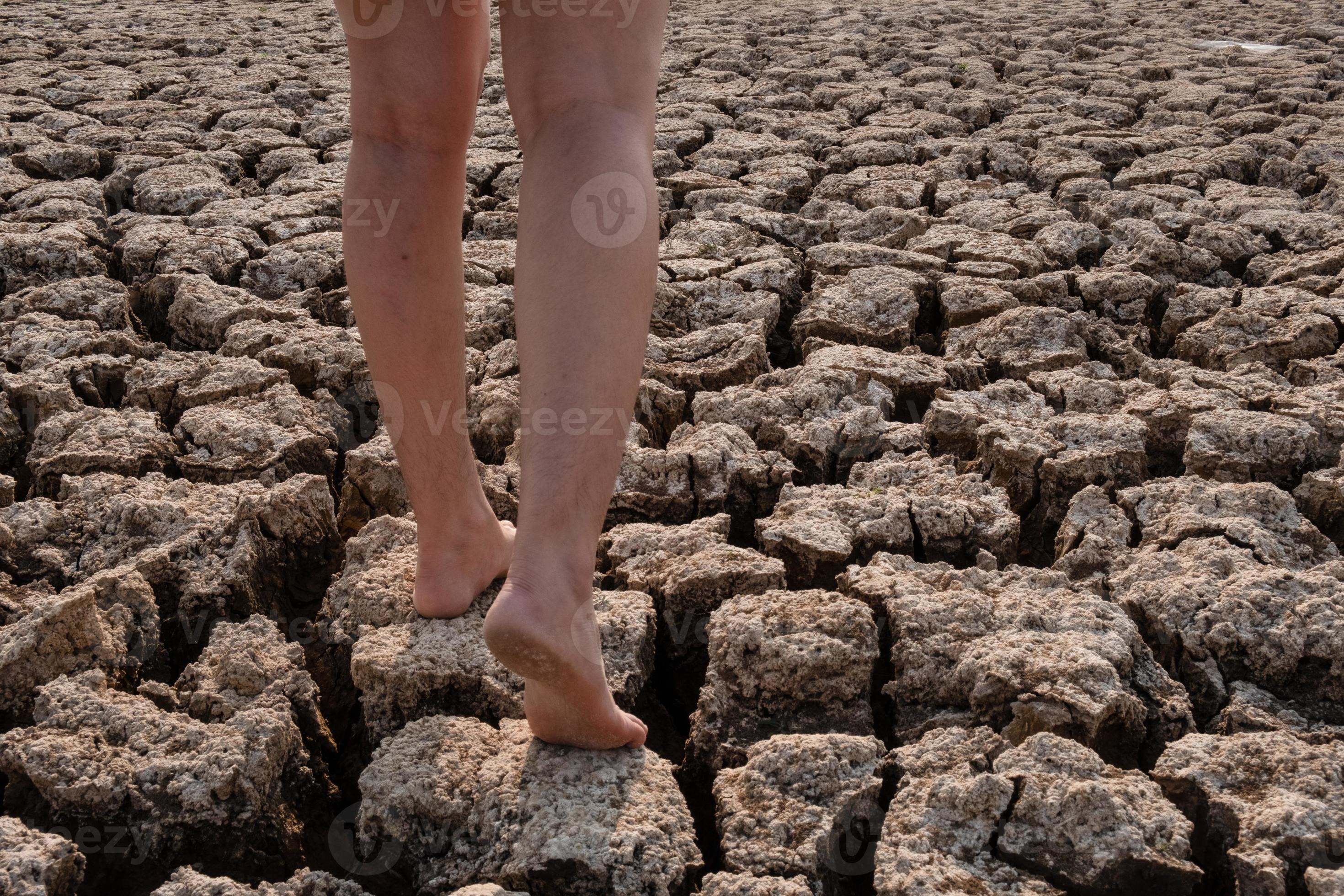 kvinna som går på sprucken torr jord foto