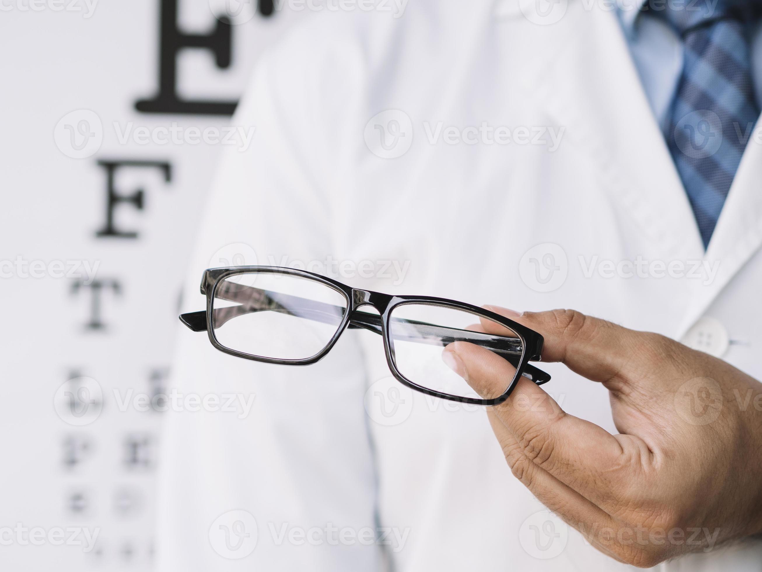 manlig läkare som håller ett par glasögon i hans händer foto