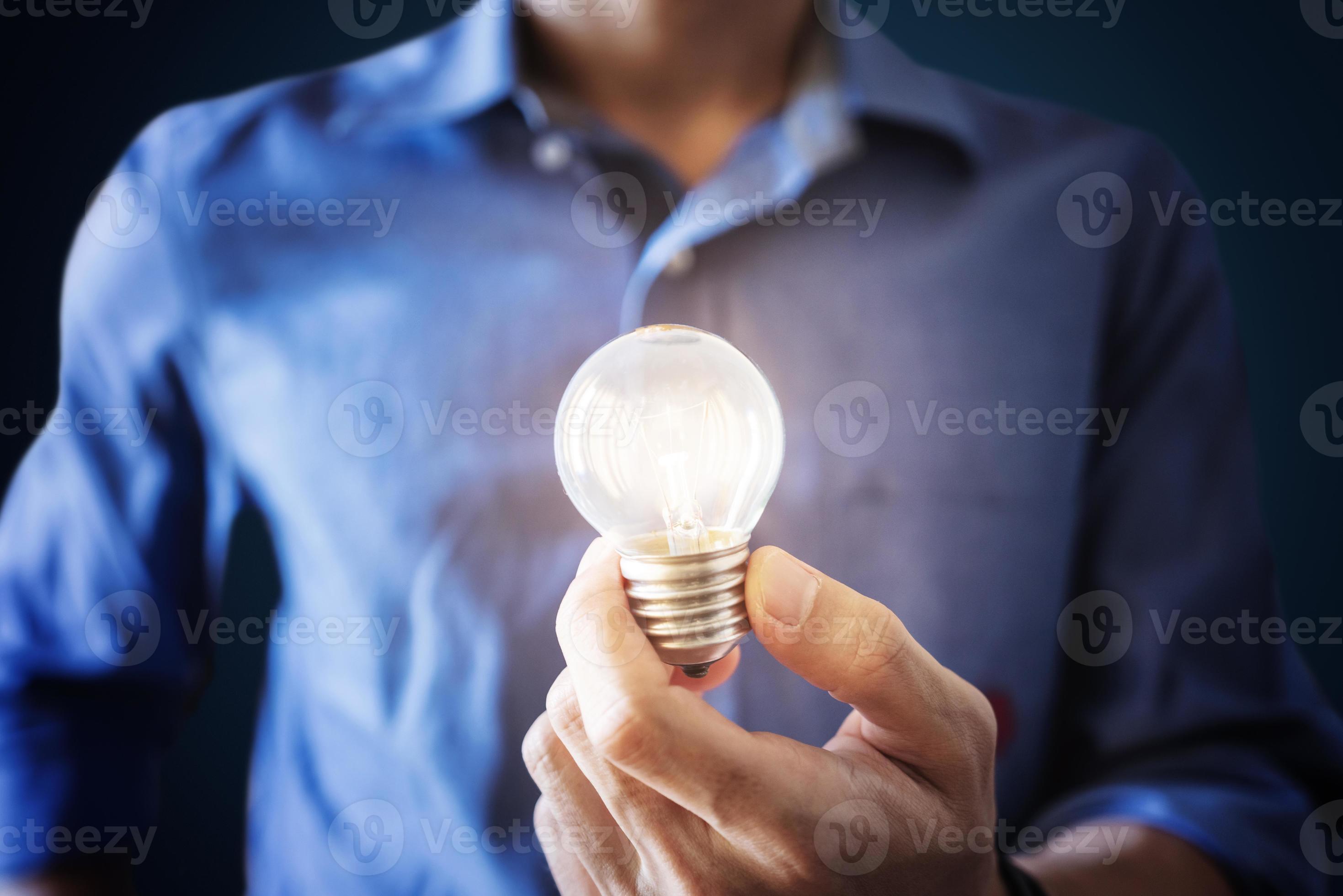 nya idéer, innovation och inspirationskoncept. en man i blå skjorta som håller glödande glödlampa foto