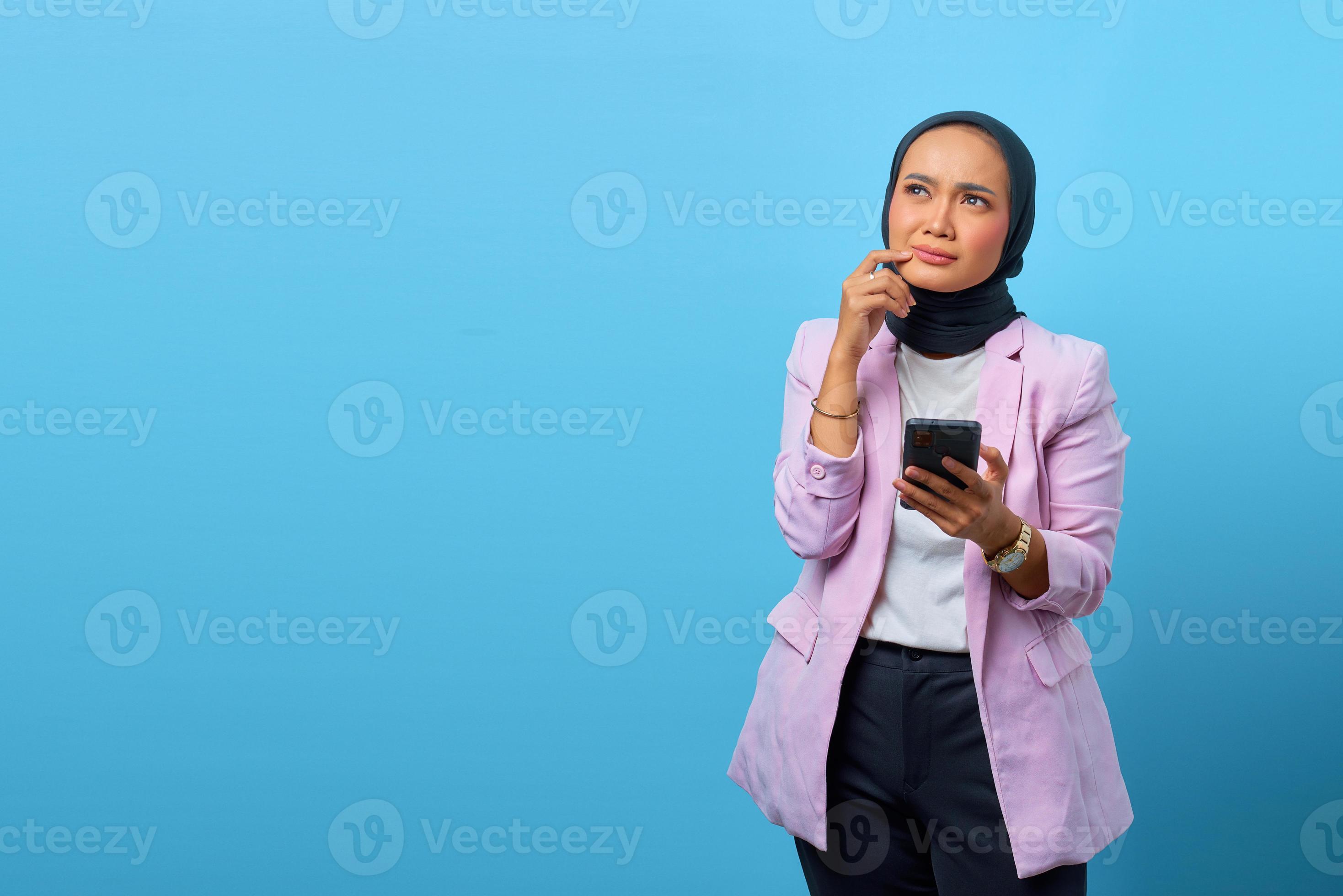 vacker asiatisk kvinna tänker på något och håller i mobiltelefonen foto