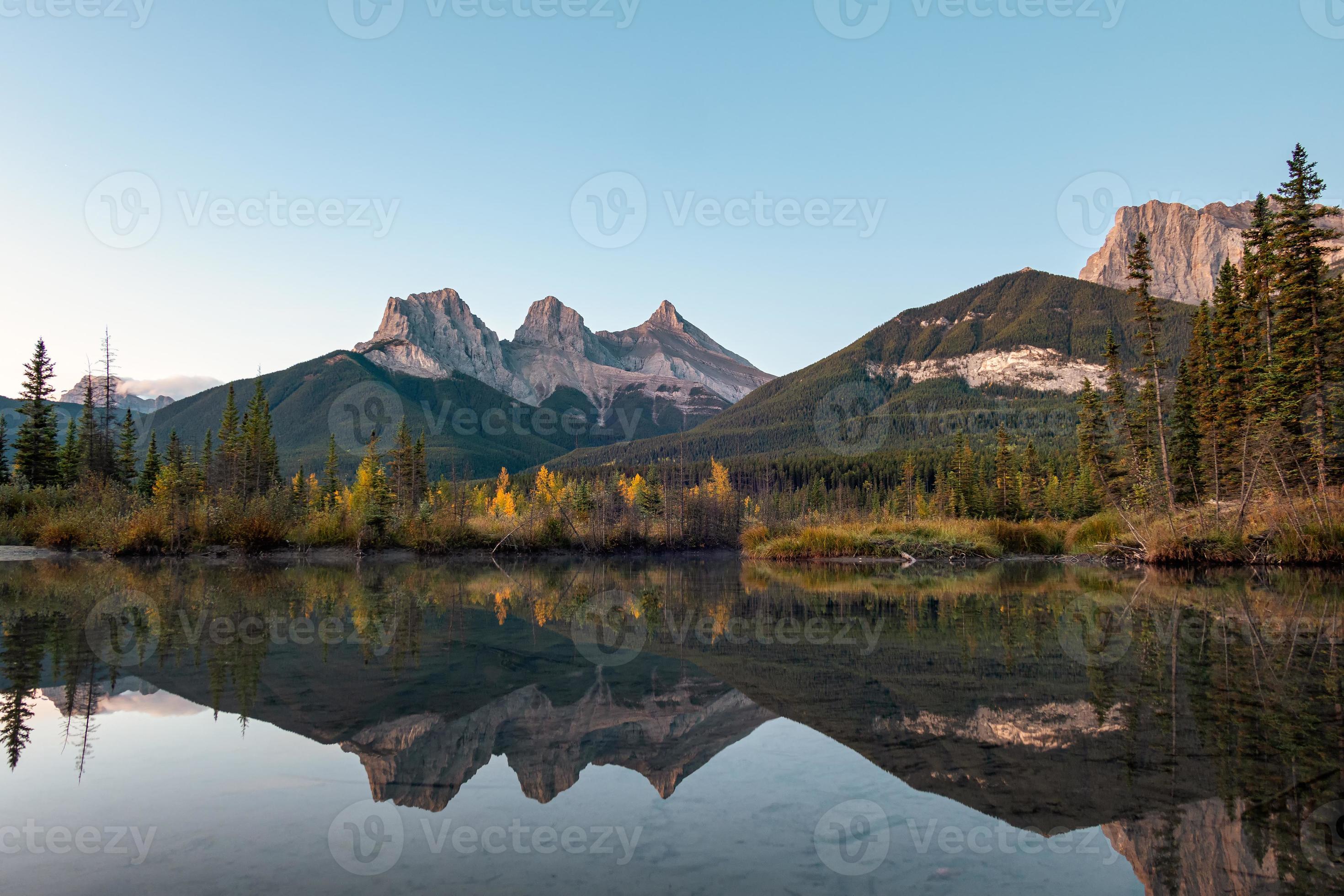 tre systrar berg av klippiga berg reflektion över bowfloden på morgonen vid Canmore, Banff nationalpark foto