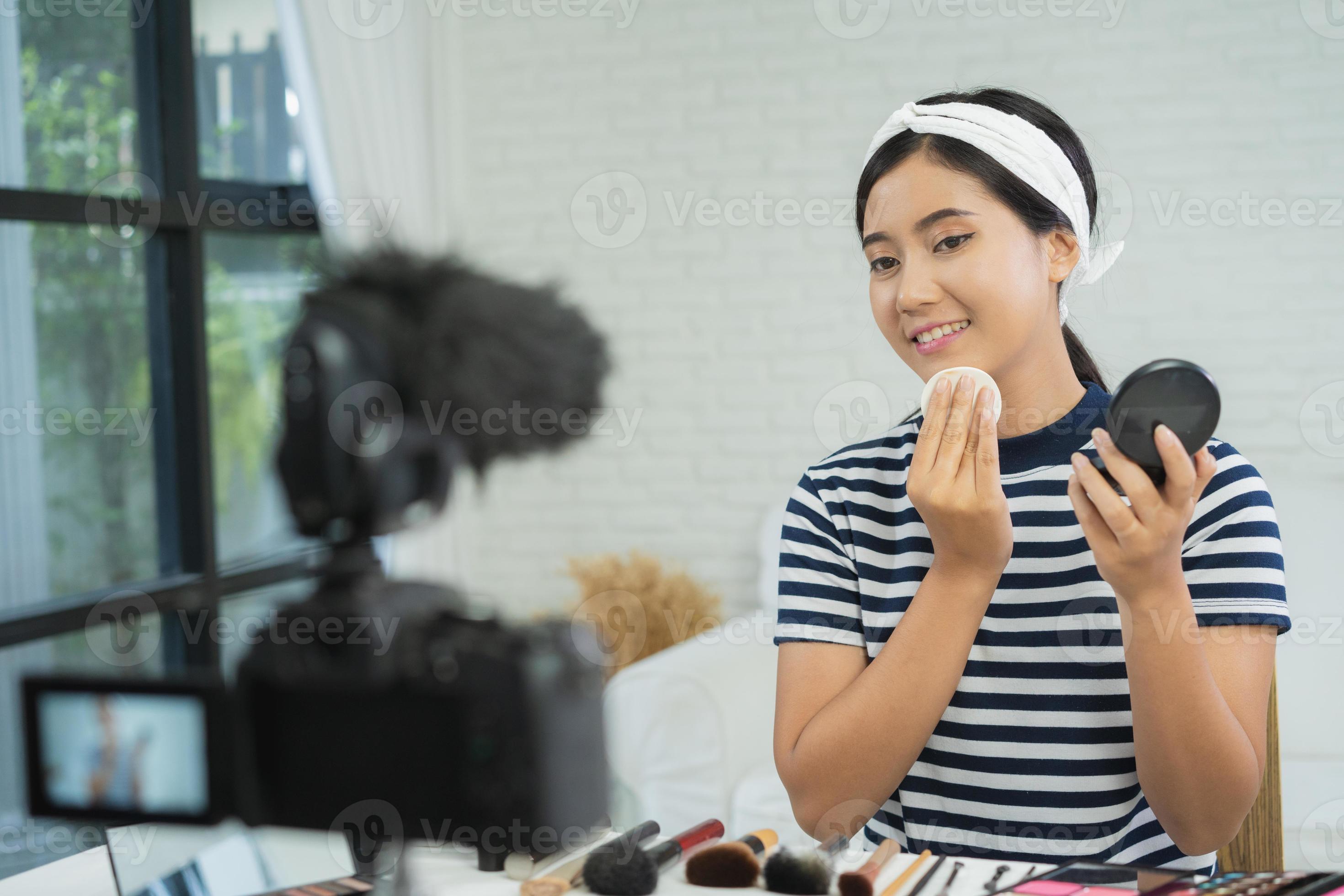 skönhetsbloggare presenterar skönhetskosmetik när han sitter framför kameran för att spela in video. vacker kvinna använder läppstift medan recensionen av sminkhandledning sänder livevideo till socialt nätverk via internet. foto
