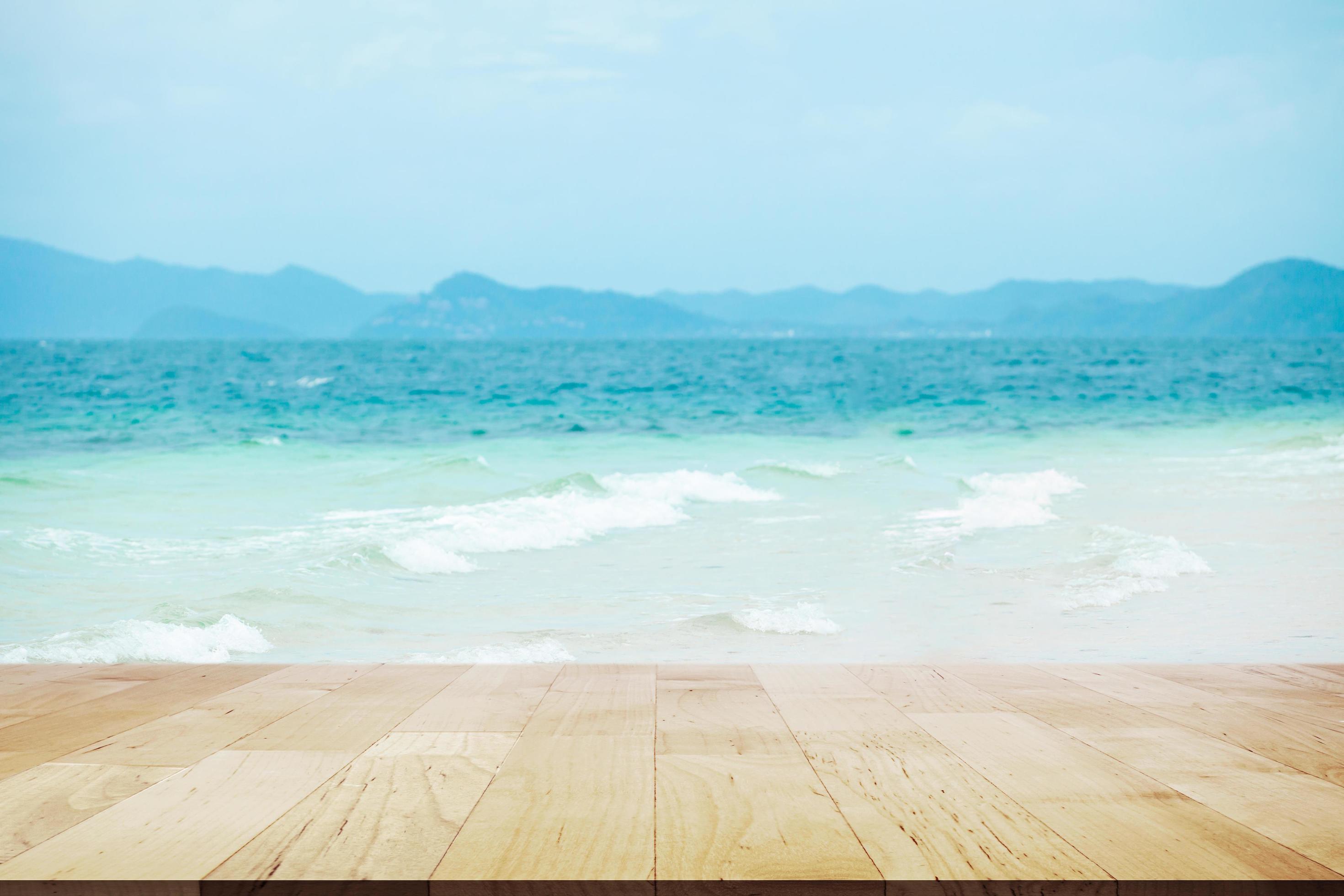 tom träbordsskiva med lampor bokeh på vacker vit sandstrand och turkost vatten. semester sommar strand bakgrund foto