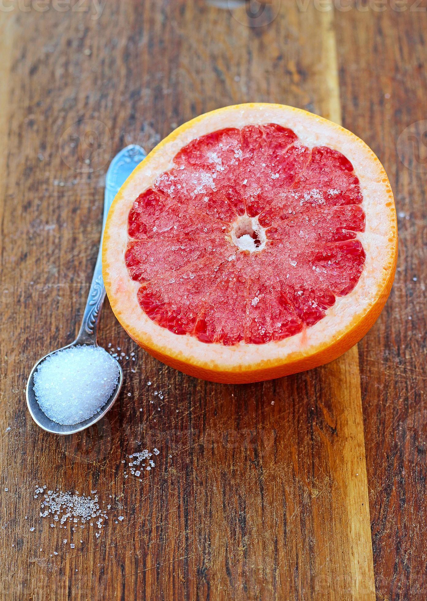 skivad grapefrukt med socker på träplanka foto