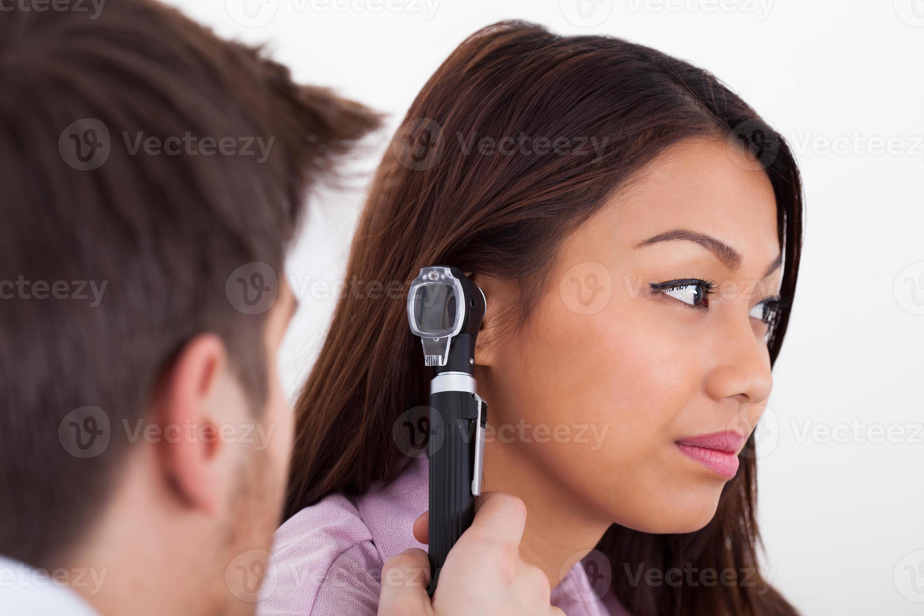 läkare som undersöker patientens örat med otoskop foto