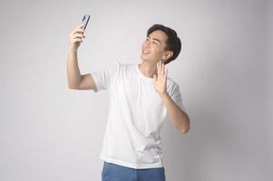 ung asiatisk man använder smartphone över vit bakgrund, teknik koncept. foto