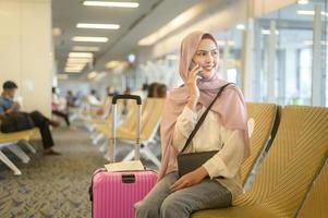 ung kvinnlig muslimsk resenär som bär resväskor på den internationella flygplatsen, resor, semester och resa koncept. foto
