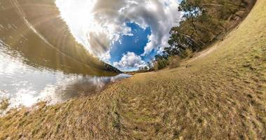 liten planetomvandling med krökning av rymden. sfärisk antenn 360 panoramautsikt på stranden av sjön i solig sommar med fantastiska moln. foto