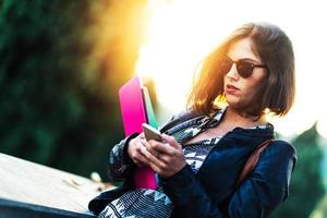 ung student vacker flicka går i staden med böcker com foto