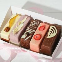 set med olika minikakor i en låda med festlig inredning oförpackad. glaserade med choklad och glasyr och bärfyllda kakor för present eller sötsaker. foto